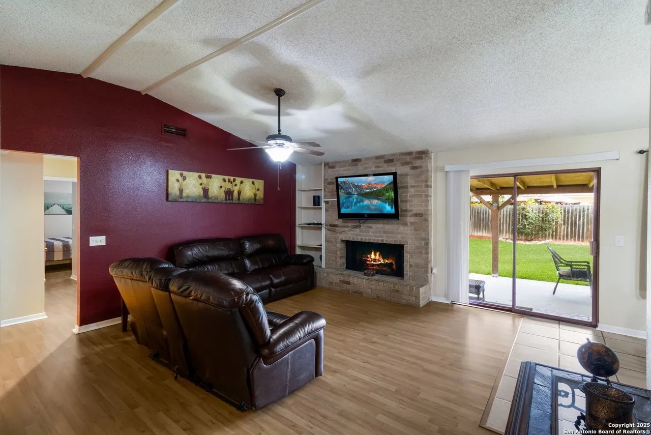 Living room with leather recliners, a brick fireplace, and sliding doors to the backyard.