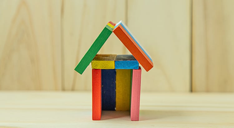Colorful wooden toy house with a striped roof and open doorway.