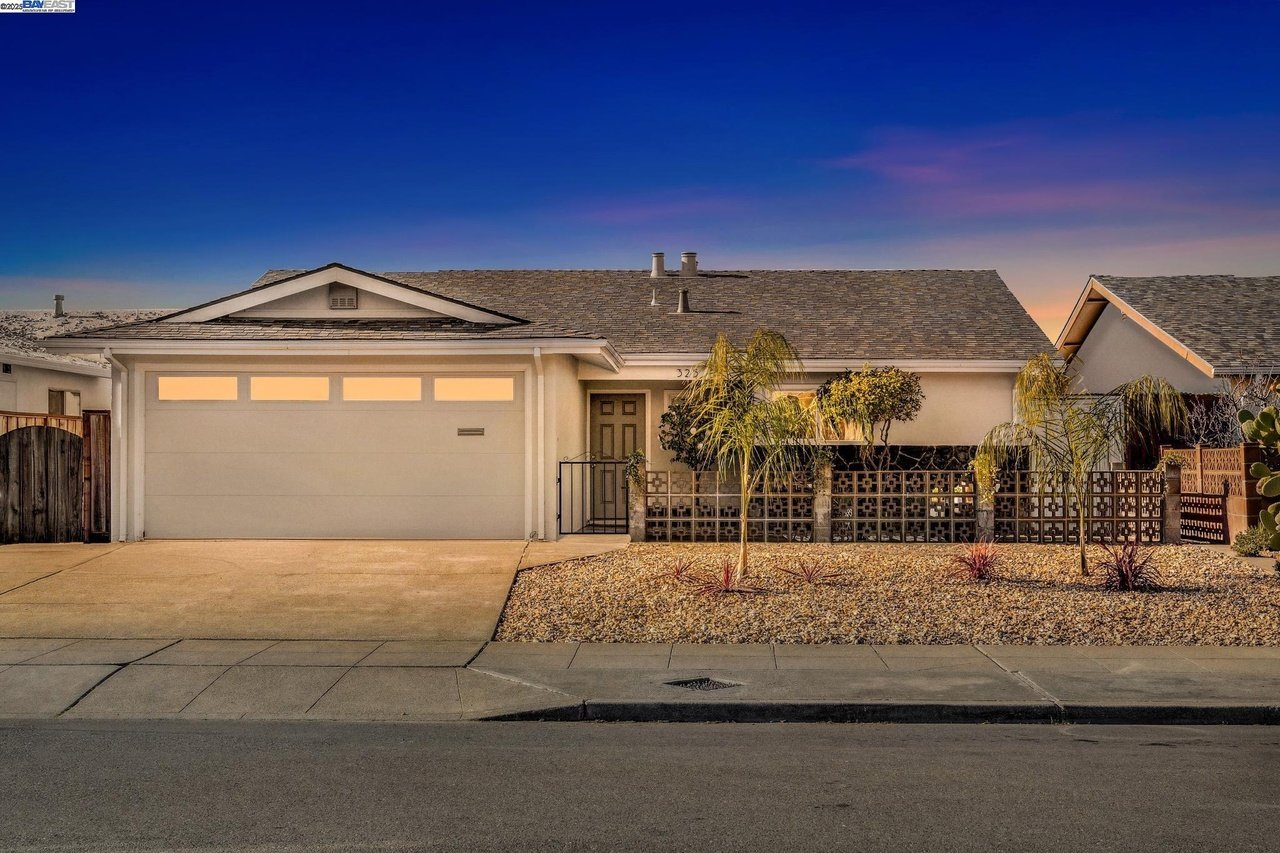 Single-story home with a two-car garage and gravel front yard at dusk.
