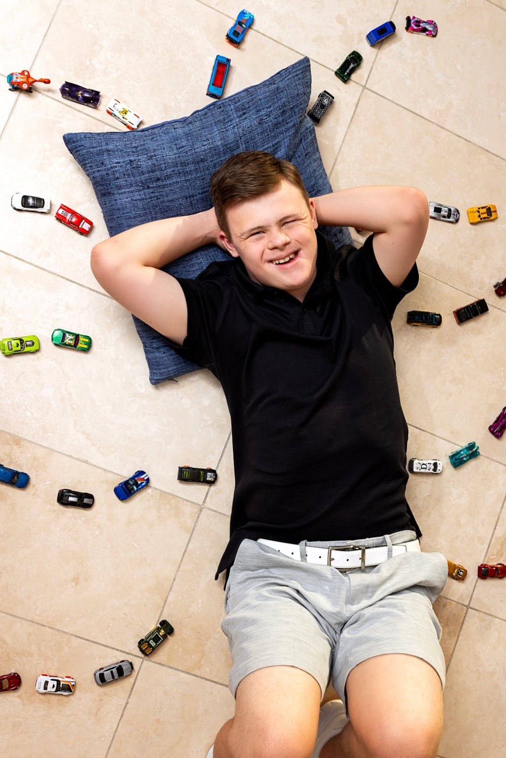 Hayes Harper smiling on the floor surrounded by his Hot Wheels cars