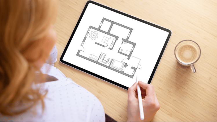 Woman reviews a home floor plan on a tablet with a stylus.