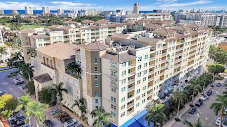 Aerial view of a beige condominium building with balconies and a city skyline beyond.