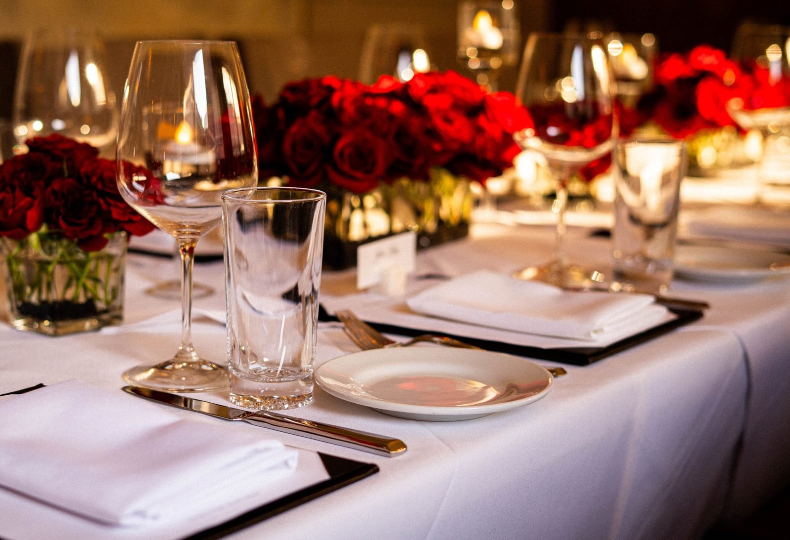 A set dining table at Selanne Steak Tavern with roses and wine glasses.