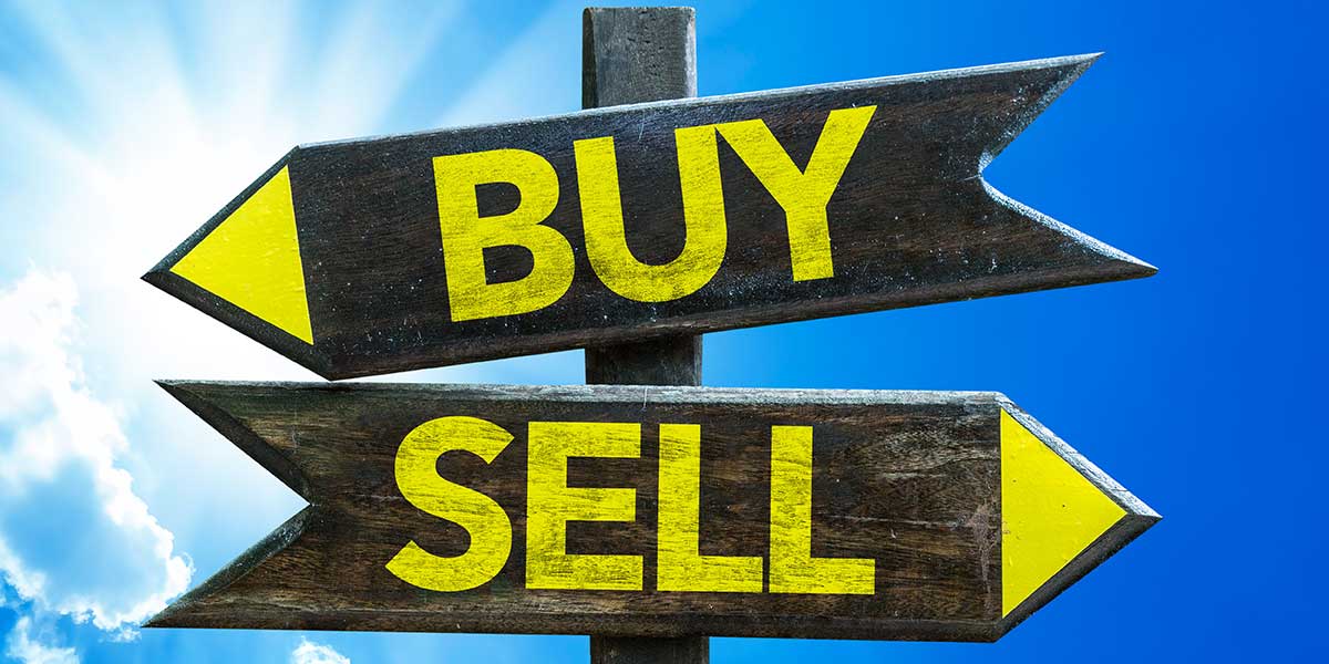 Wooden directional signs marked BUY and SELL against a blue sky.