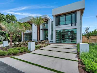 Modern two-story home with large windows and a landscaped driveway divided by strips of grass.