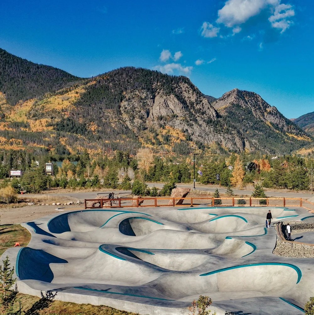 Frisco Adventure Park pump track with teal-edged turns beneath autumn-colored mountain slopes.
