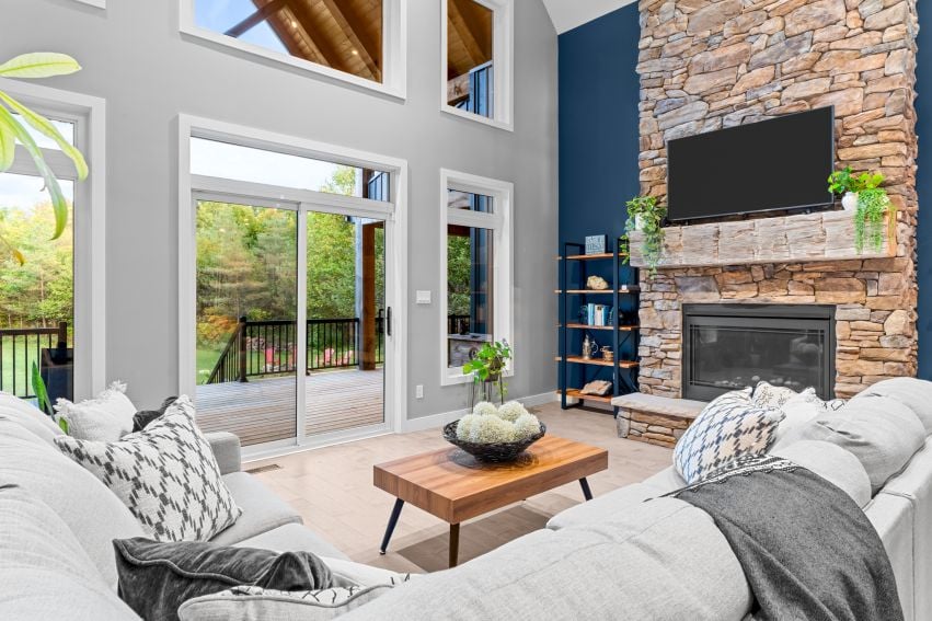 Living room with a vaulted ceiling, stone fireplace, and sliding doors opening onto a deck.
