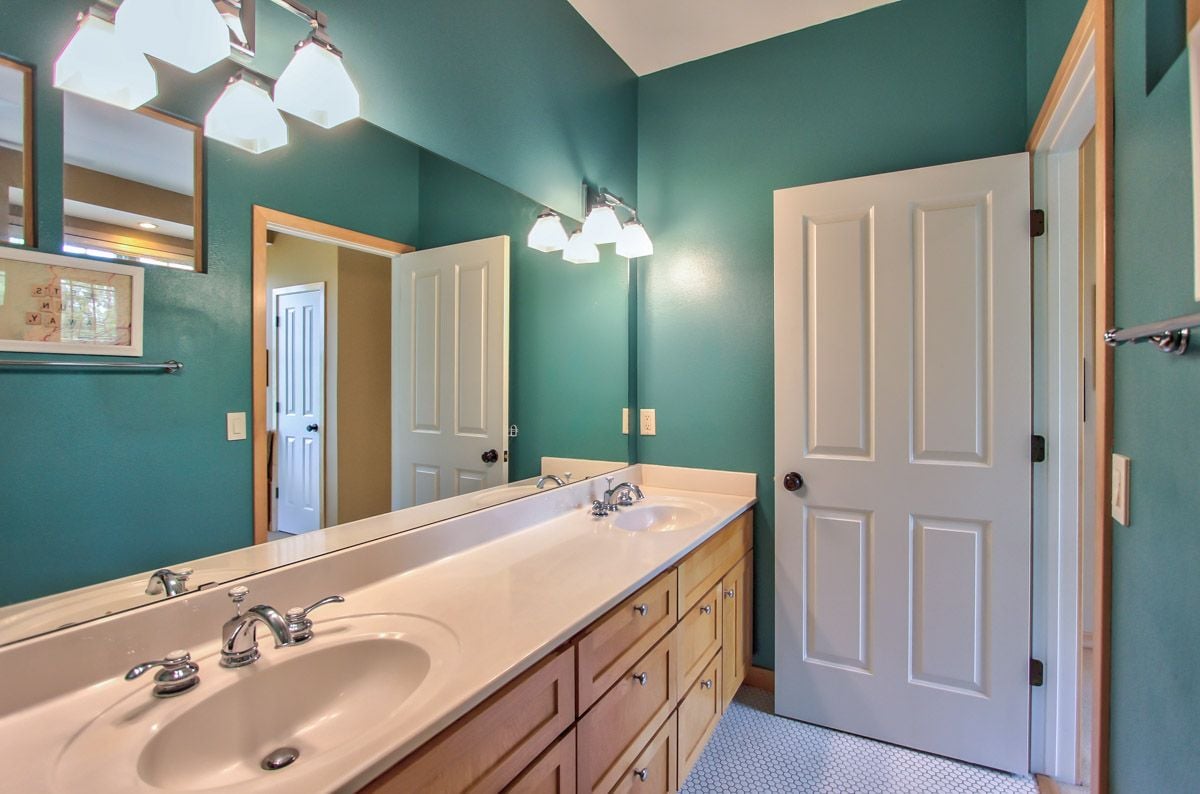 Bathroom with teal walls, a long wood vanity, and a large mirror.