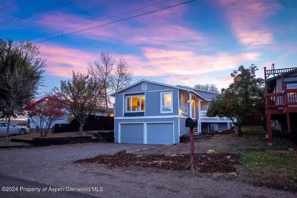 Blue-gray two-level house with a double garage beneath a pink dusk sky.