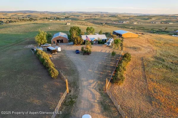 Rural property with several outbuildings, a long driveway, and open fields.