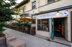 Boulder restaurant exterior with a sidewalk patio, outdoor umbrellas, and a banner above the entrance.