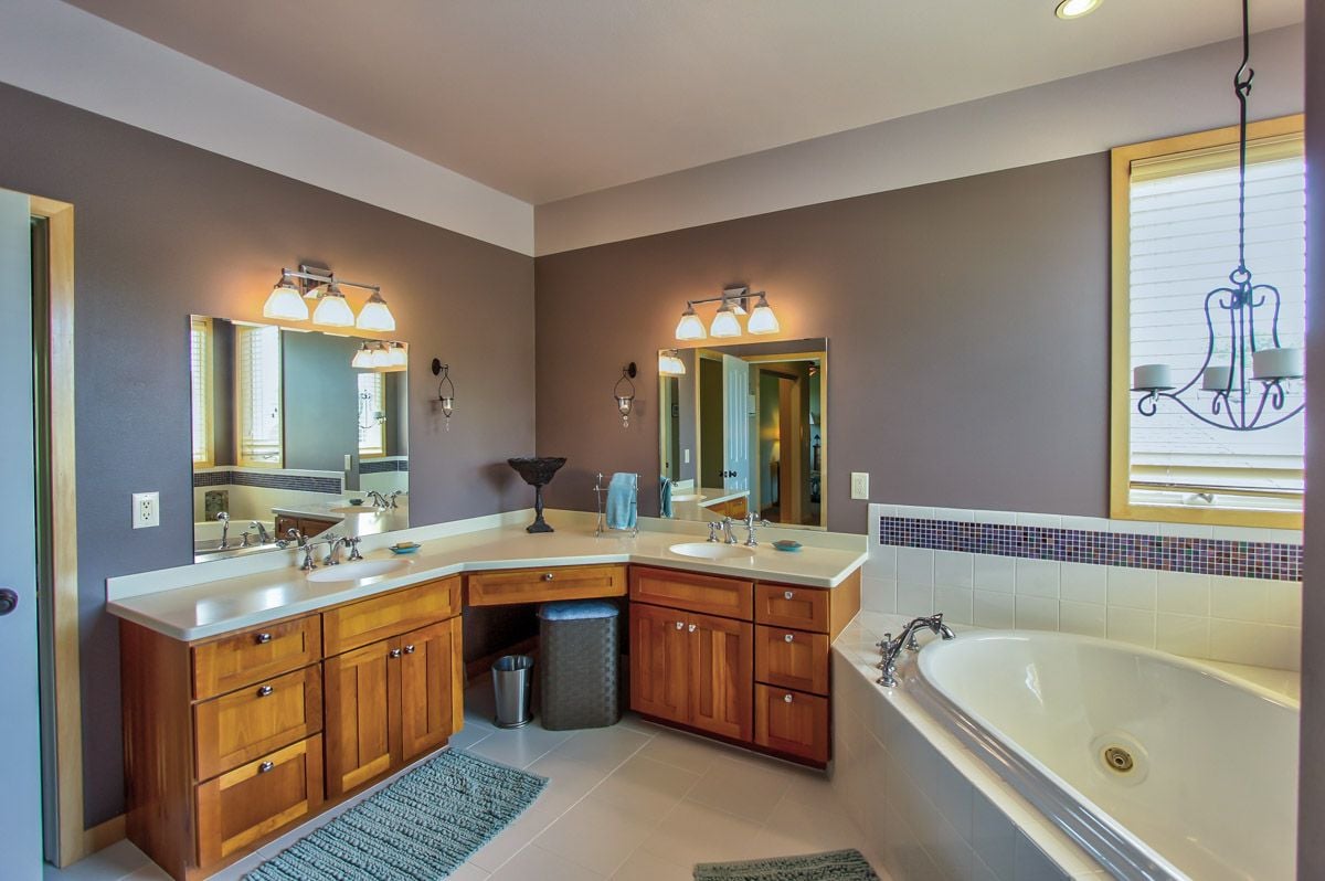 Spacious bathroom with a wooden double vanity, large mirrors, and a built-in soaking tub.