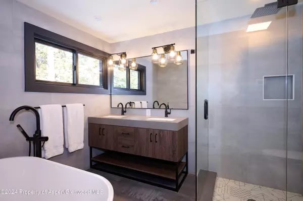 Modern bathroom with a dark wood vanity, wide mirror, and glass-enclosed shower.