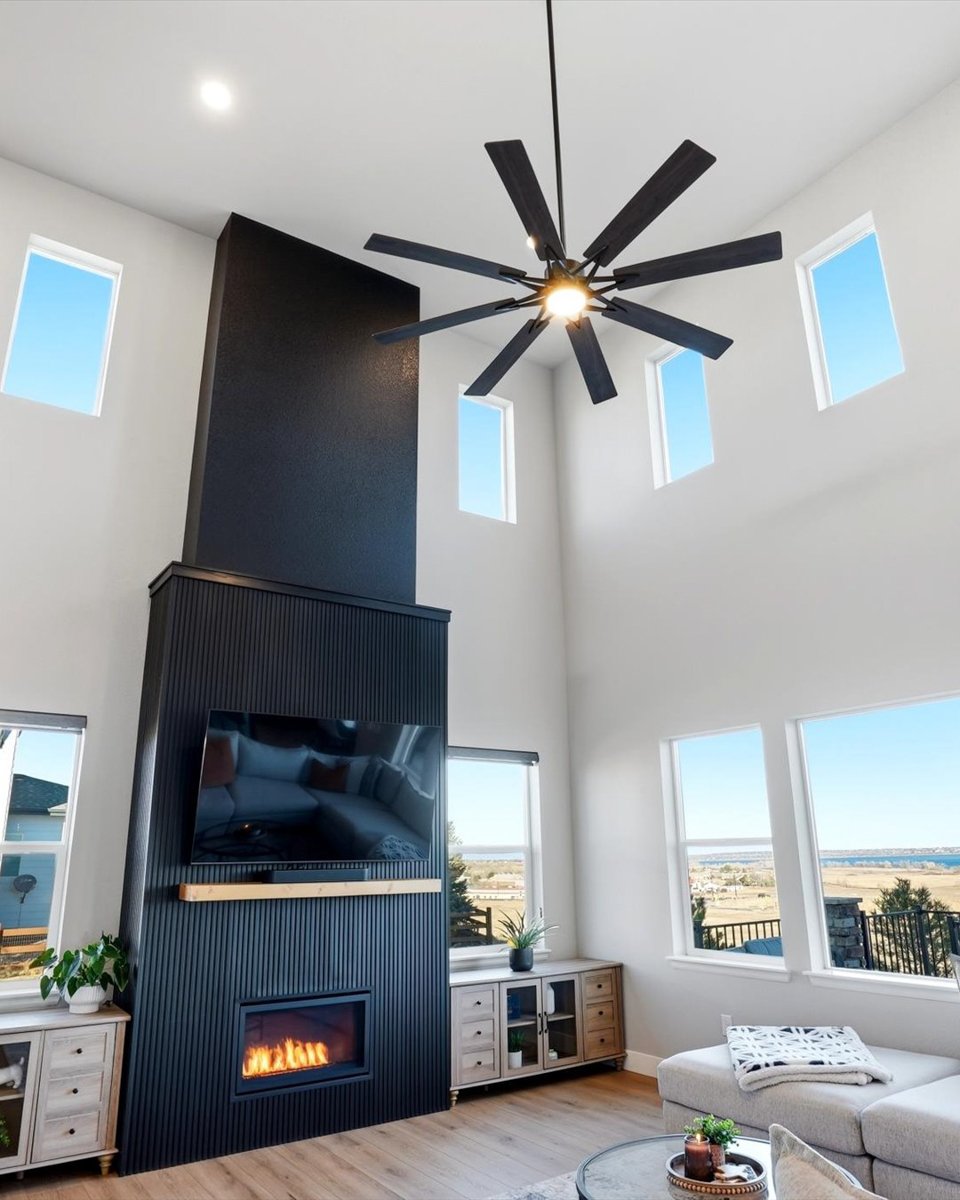 Modern living room with high ceilings, fireplace, and large windows in a Denver suburbs home for sale.