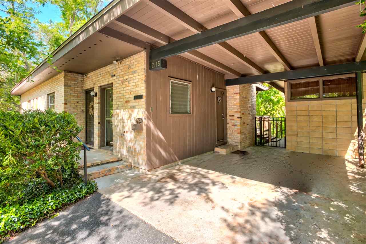 A charming home featuring a covered porch, surrounded by a lush tree, creating a welcoming outdoor space.