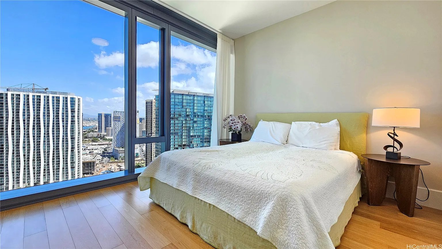 Bedroom with floor-to-ceiling windows overlooking a city skyline.