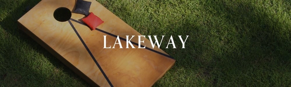 Cornhole board and beanbags on grass beneath the word “Lakeway.”