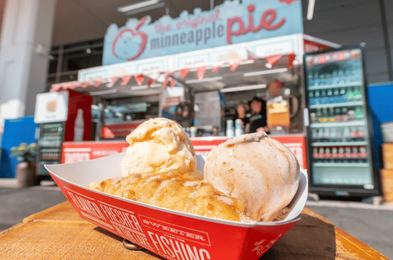 Fried pineapple pie topped with two scoops of ice cream at a concession stand.