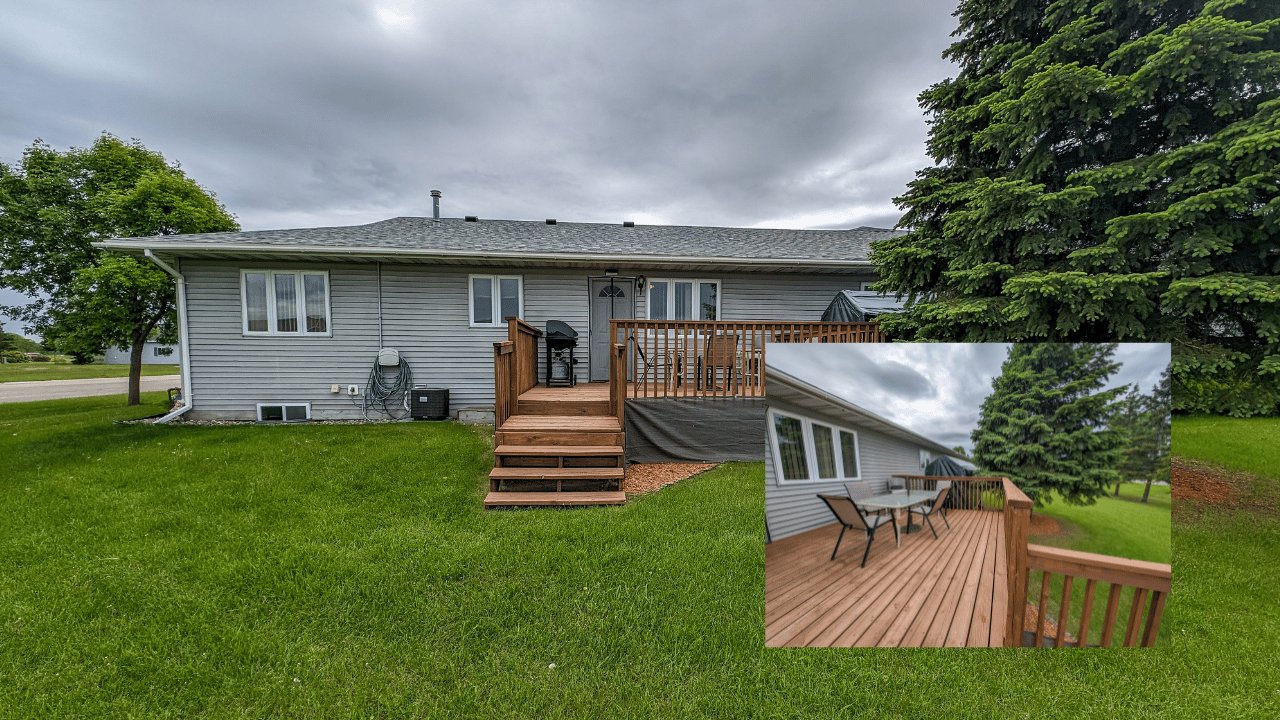 Gray-sided house with a wooden deck, patio dining set, and broad green lawn.