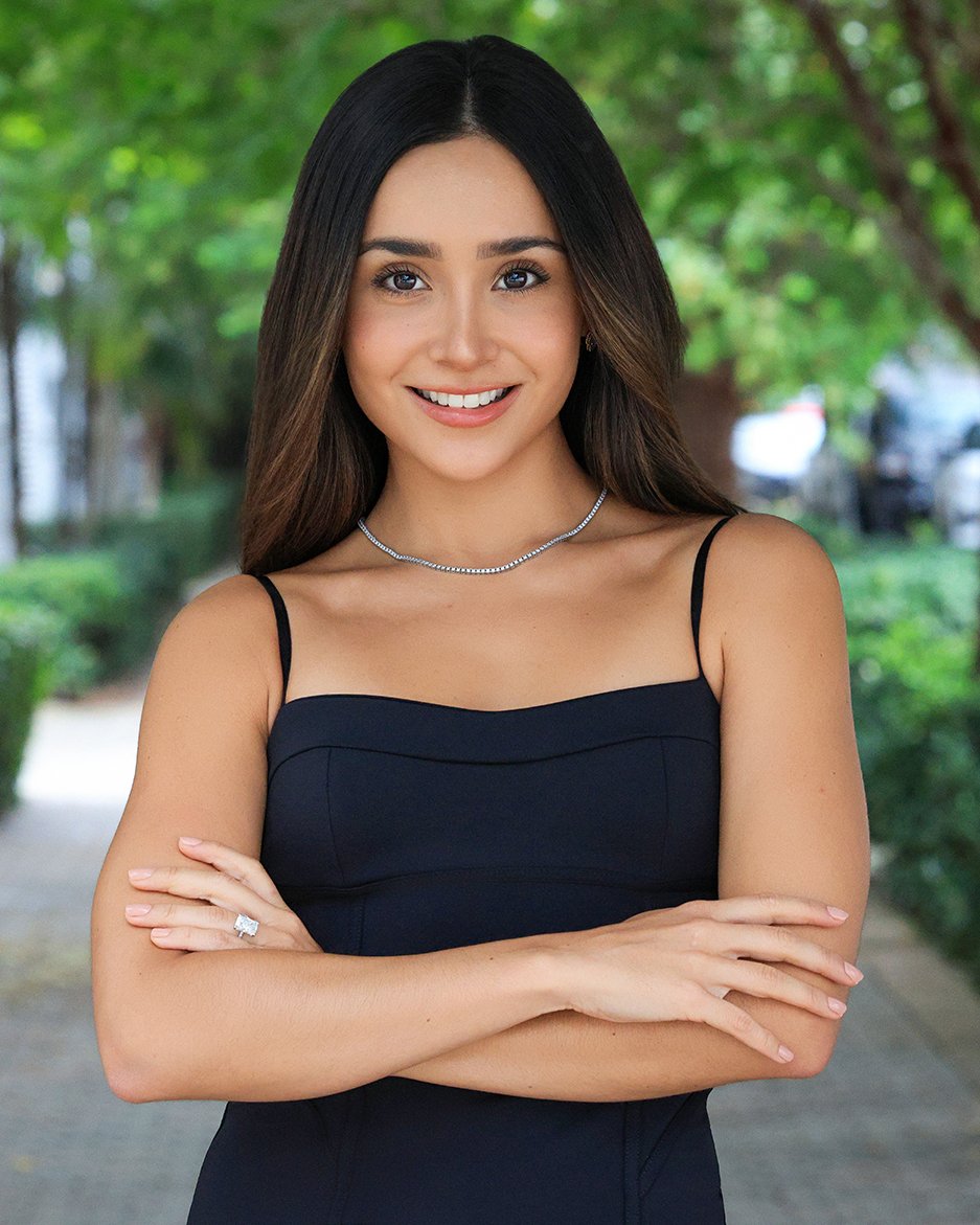 Giovanna Grasso smiling with her arms crossed in a black dress outdoors.