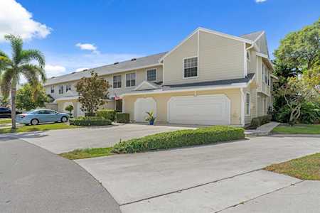Two-story beige townhouse with attached garages and landscaped frontage in Fairfield, Boca Raton.