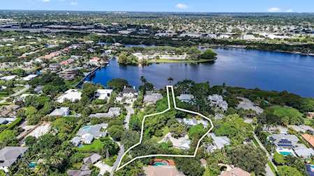 Aerial view of a marked property lot near a lake, surrounded by homes and trees.