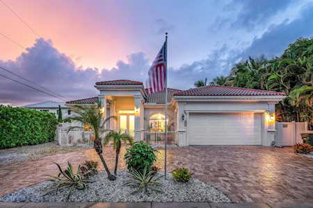 Single-story home with a tiled roof, paver driveway, and American flag at sunset.