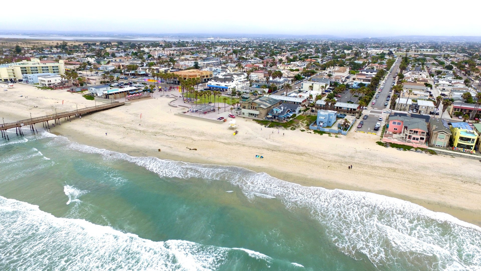 Drone aerial of the Imperial Beach shoreline with the pier, the surf line and the tightly packed beach blocks behind the sand, May 2016
