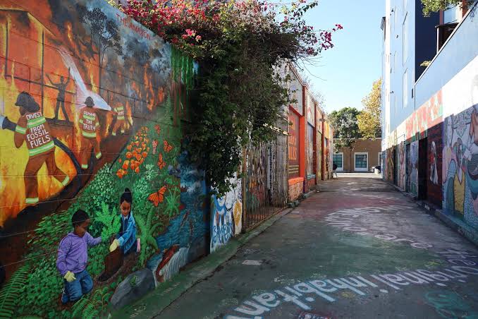 Vibrant street art murals lining narrow San Francisco alleyway with pathway