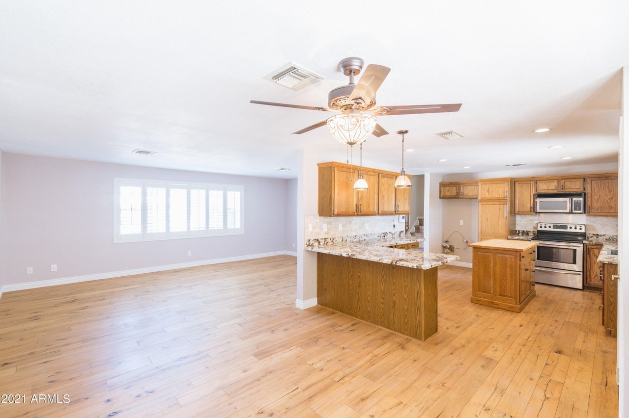 Open kitchen and living area with wood floors, honey-colored cabinets, and a large island.