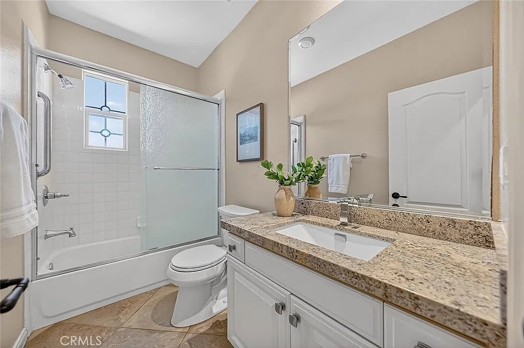 Bathroom with a frosted-glass shower enclosure and a granite-topped white vanity.