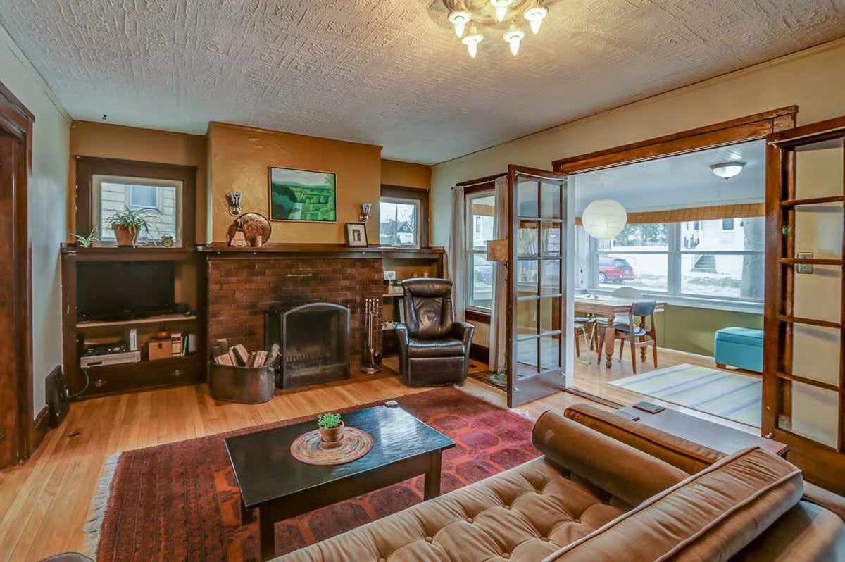 Living room with brick fireplace, built-in shelving, and glass-paneled doors to a dining area.