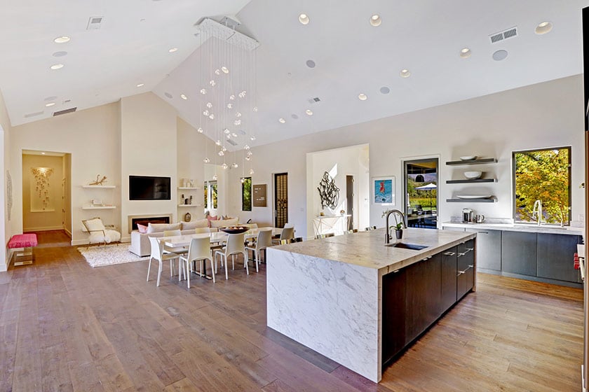 Open-plan kitchen and dining area with a large marble island and cascading pendant light.