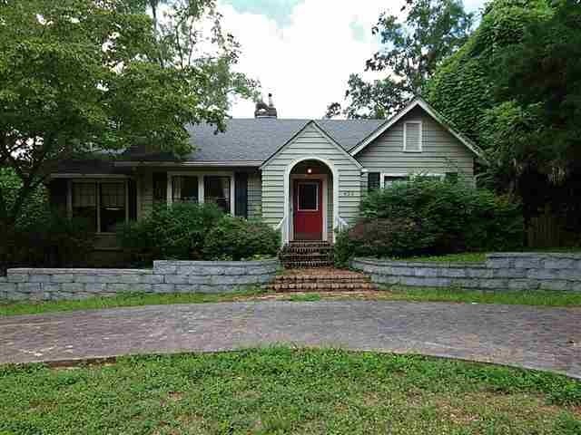 A house with a clear driveway leading up to its entrance, surrounded by greenery and a well-maintained lawn.