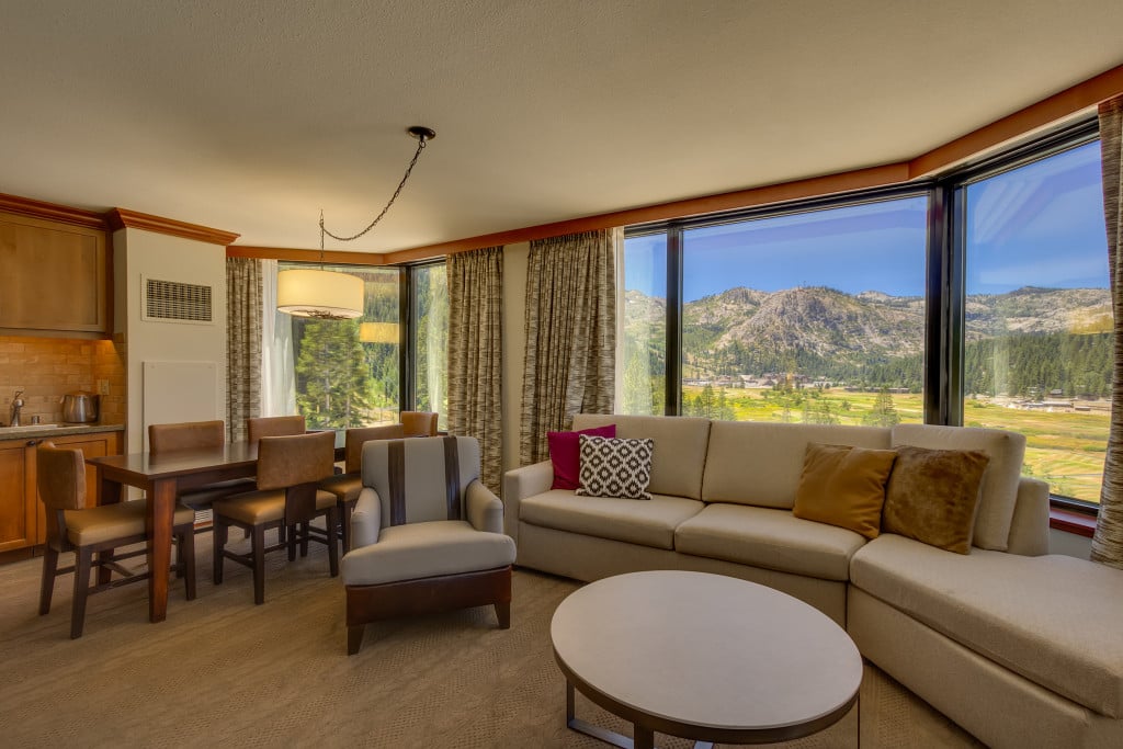 Condo living room with a sectional sofa and expansive mountain views through large windows.