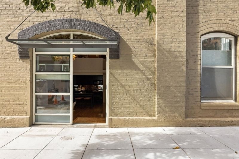 Close-up of the arched entryway of a brick building at 400 Spear Street, featuring a modern glass awning and door.