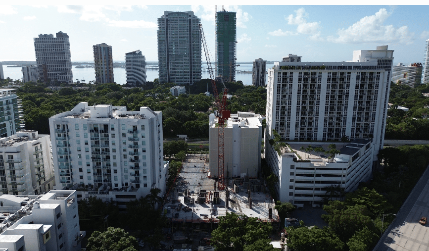Brickell construction site with a tower crane, surrounded by high-rise condos and greenery.