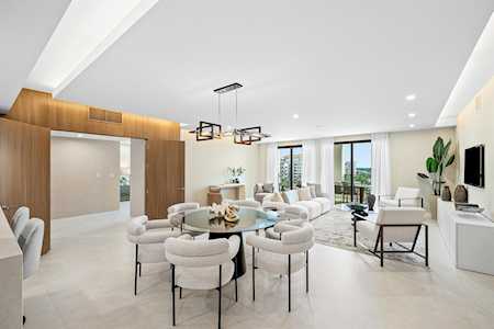 Modern living and dining room with white furnishings and a warm wood accent wall.