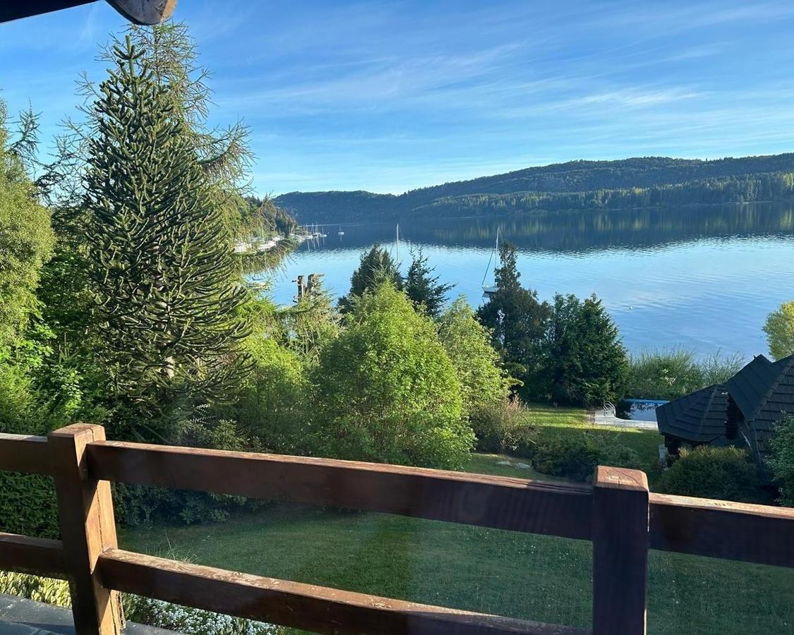 Lakefront garden and pool overlooking a calm lake, sailboats, and wooded hills.