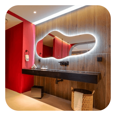 Modern bathroom with an illuminated mirror, floating vanity, wood-look panels, and red accent wall.