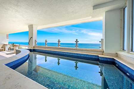 Indoor swimming pool overlooking the ocean, with blue tile and a curved edge.