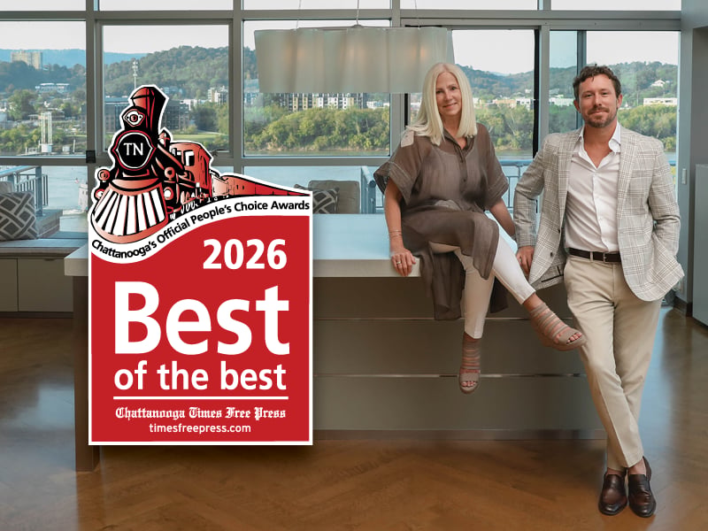 Two real estate agents pose in a bright office beside a 2026 Best of the Best award.