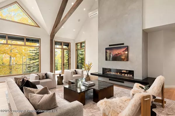 Vaulted living room with a stone fireplace, tall windows, and contemporary furnishings.