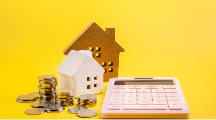Miniature houses, stacked coins, and a calculator on a bright yellow background.