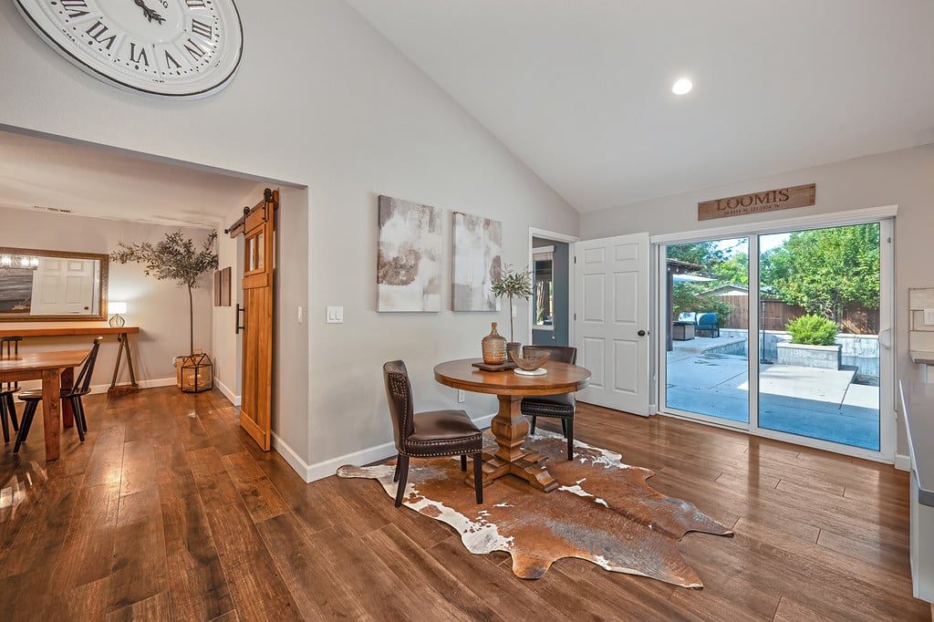 Dining area with a round wooden table and sliding glass doors overlooking the patio and pool.