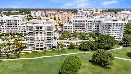 Aerial view of mid-rise residential buildings beside landscaped lawns, trees, and walking paths.