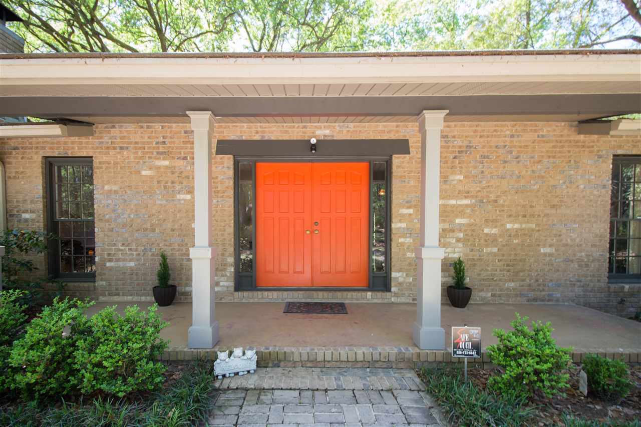 A brick home featuring an orange door and a charming brick walkway leading to the entrance.