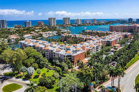 Aerial view of East Boca homes and condominiums beside waterways, with the oceanfront skyline in the distance.