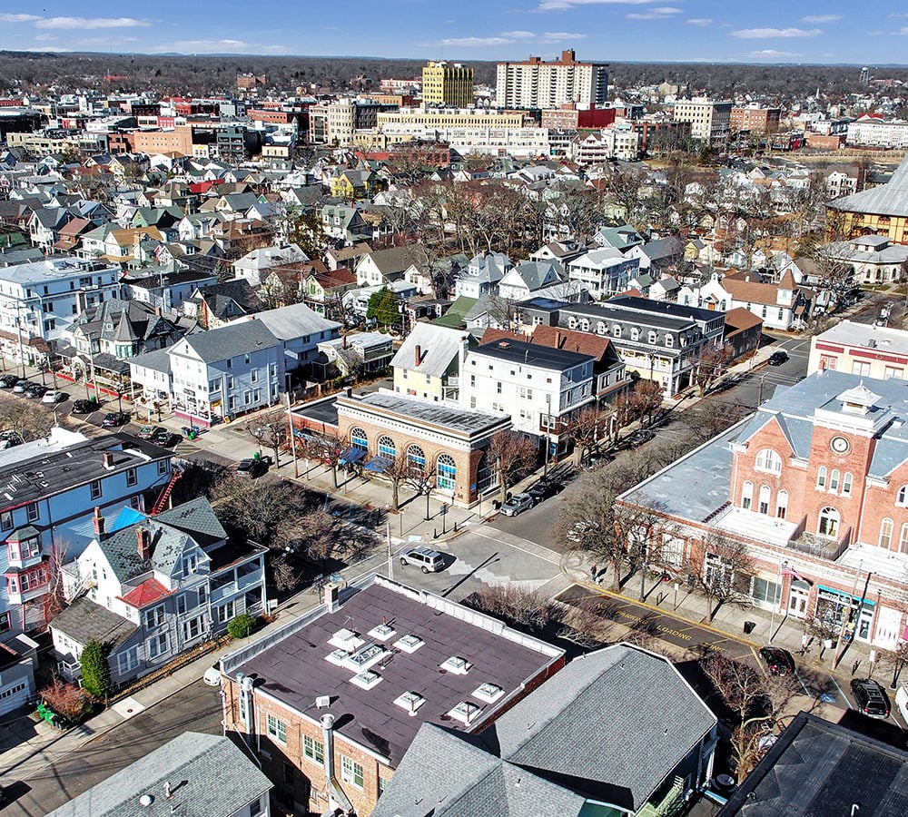 Aerial view of a town center with dense homes, commercial buildings, and taller buildings in the distance.