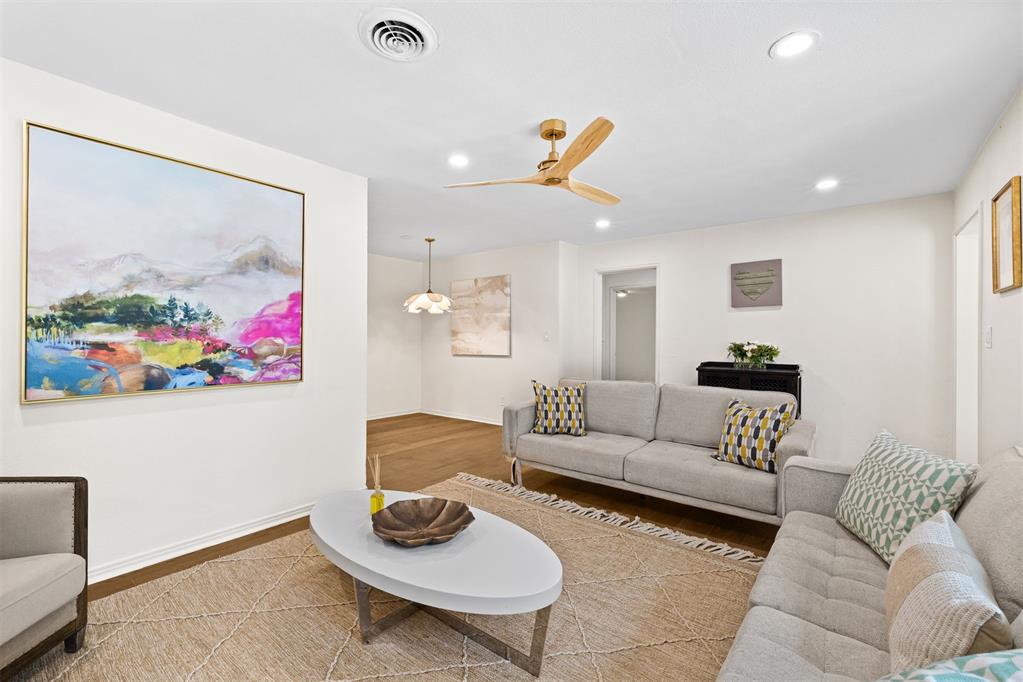 Staged living room with gray sofas, colorful abstract art, and a white oval coffee table.